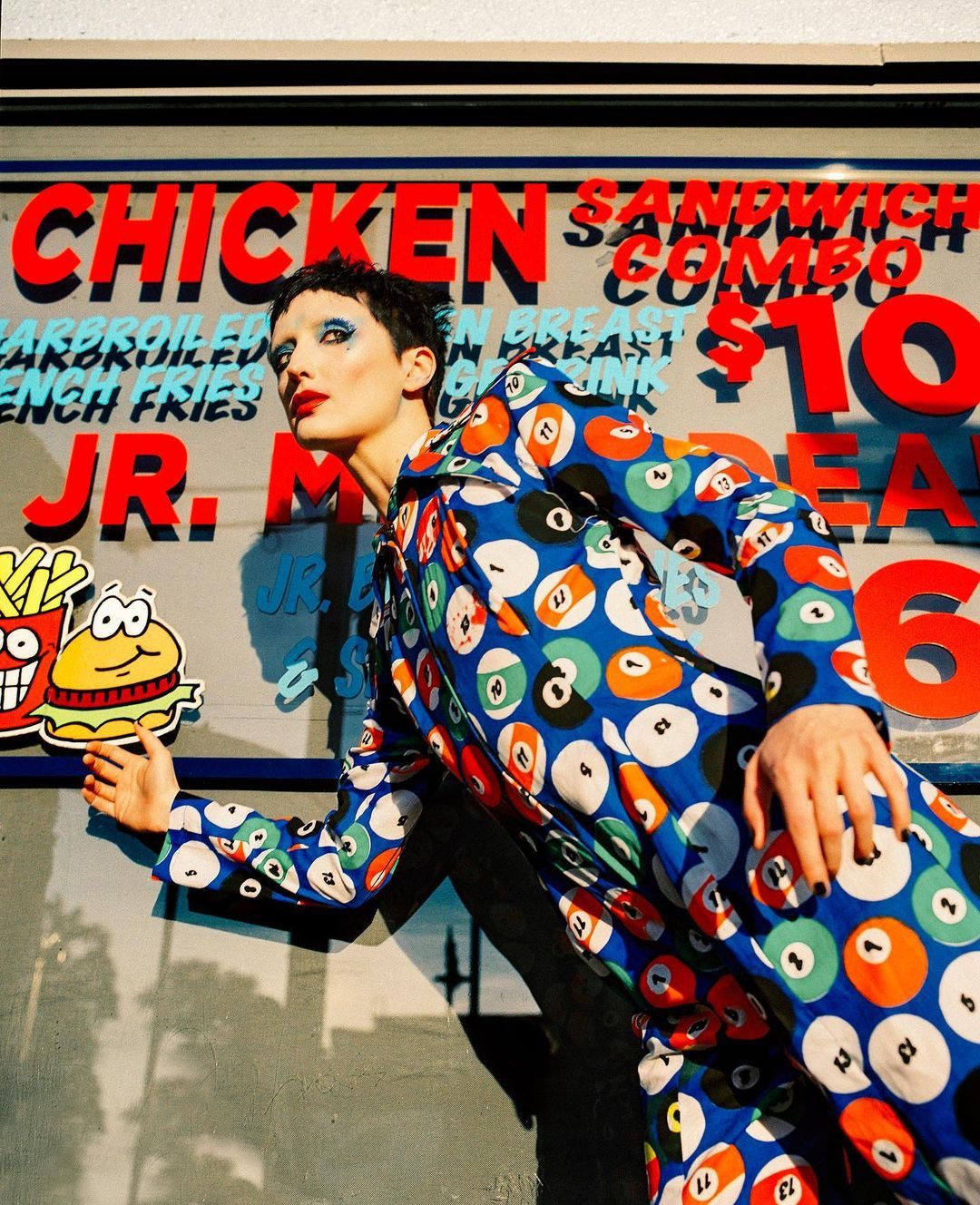Performer against a hand-painted fast-food sign