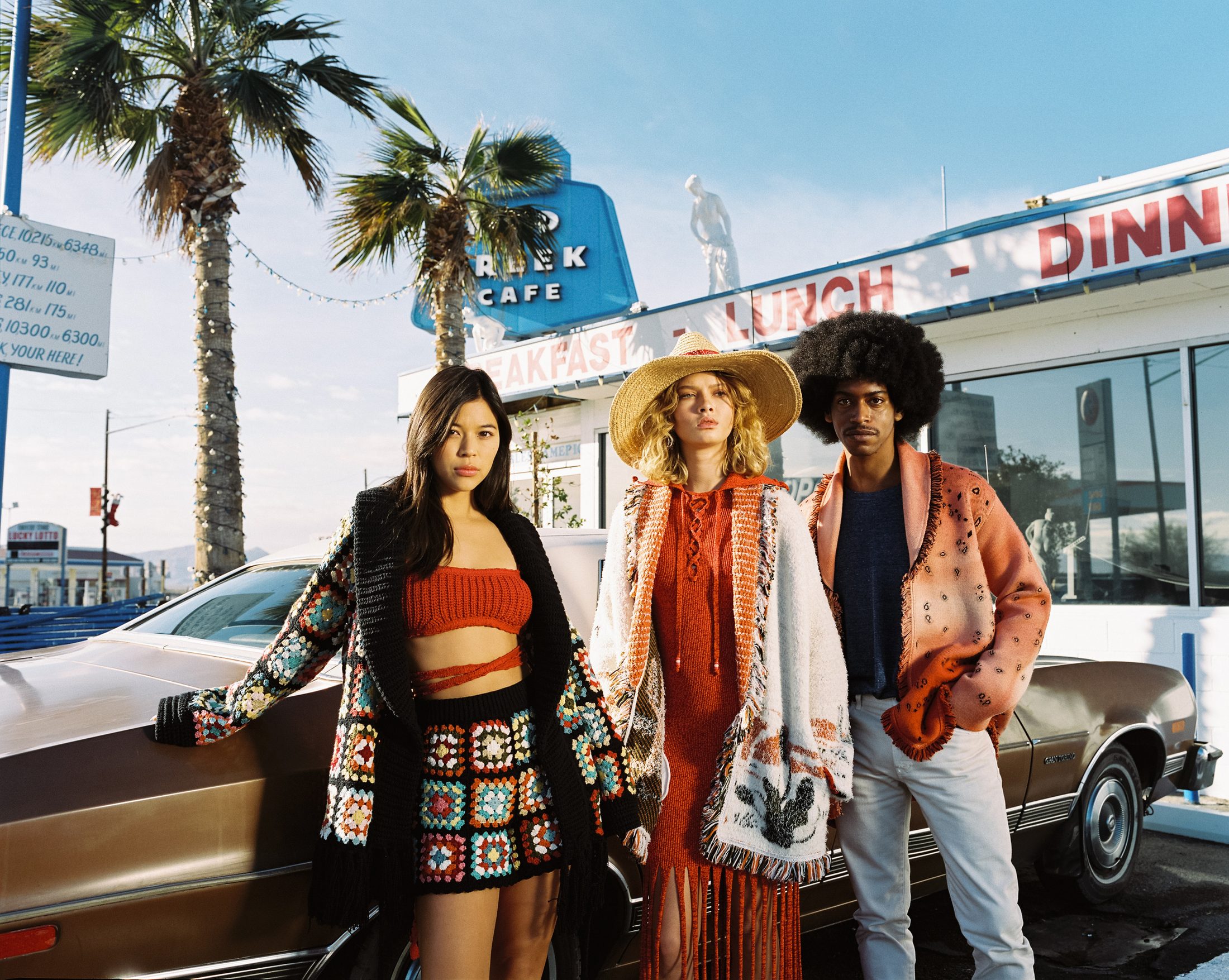 Three performers holding a beat outside a roadside diner
