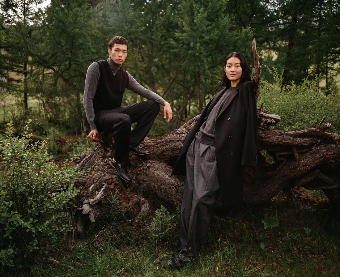 Two performers styled in black in a pine forest