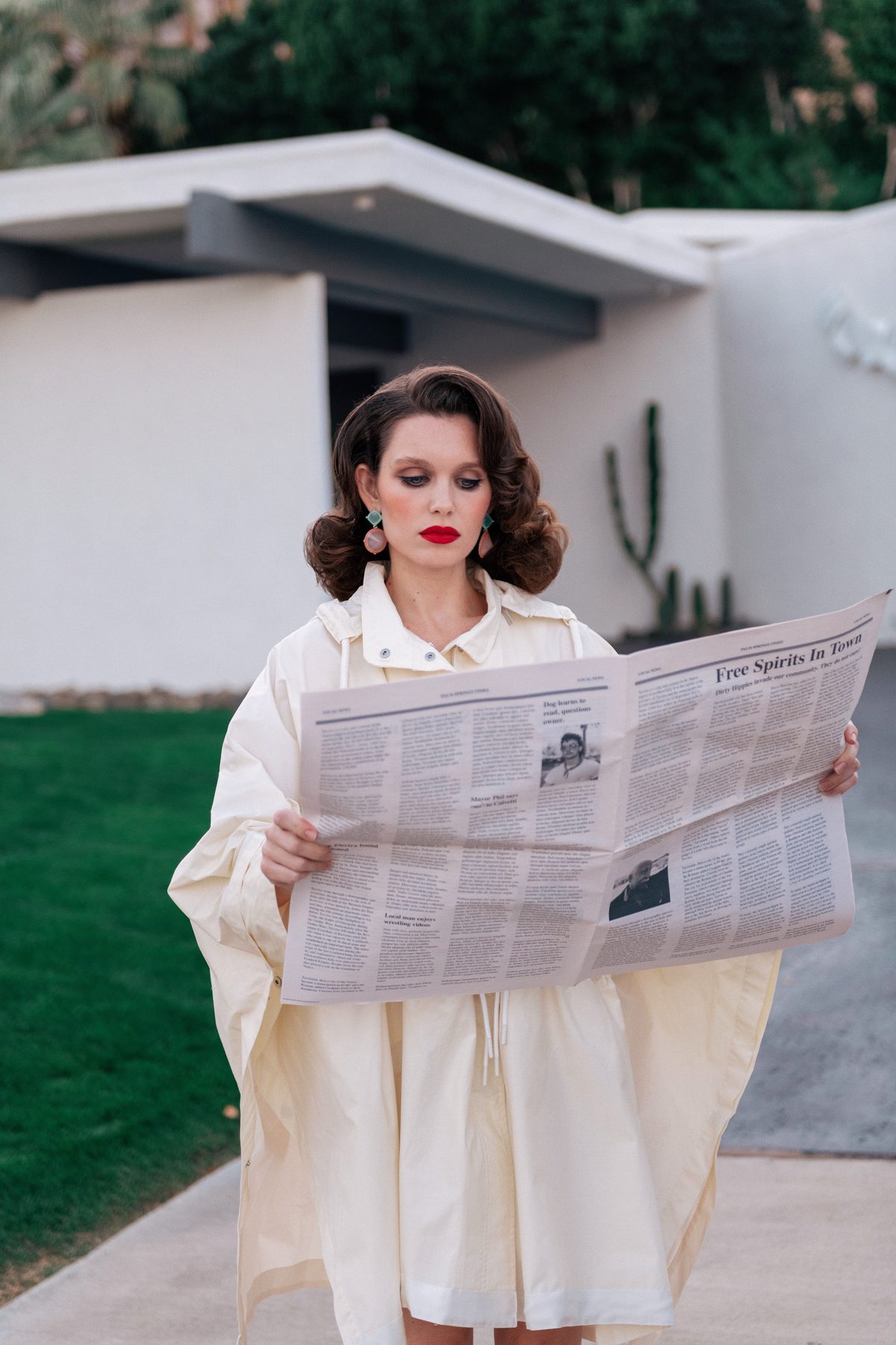 Woman reading a newspaper on a suburban lawn, playing it dead straight