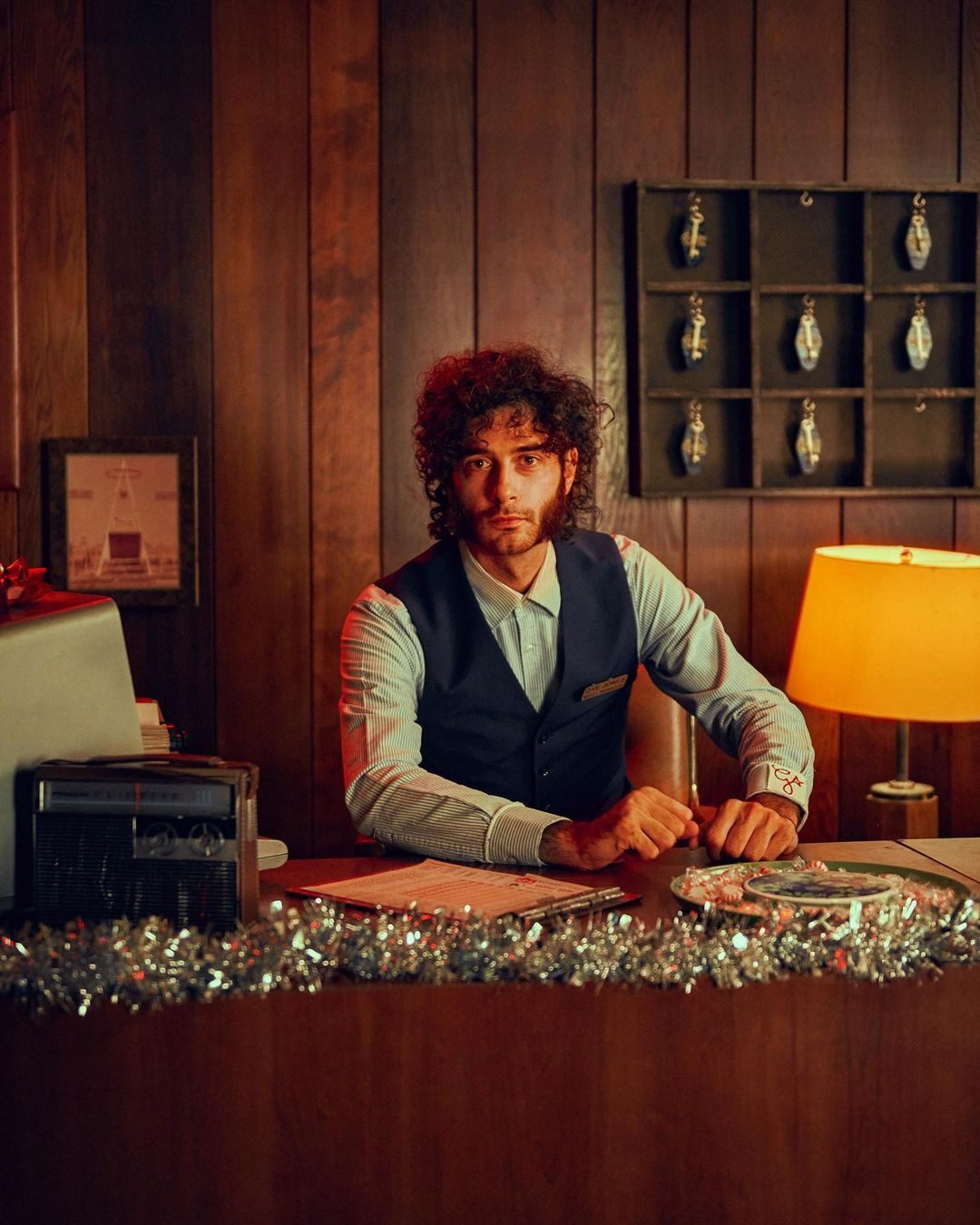 A man at a wood-panelled desk in a warm, art-directed interior