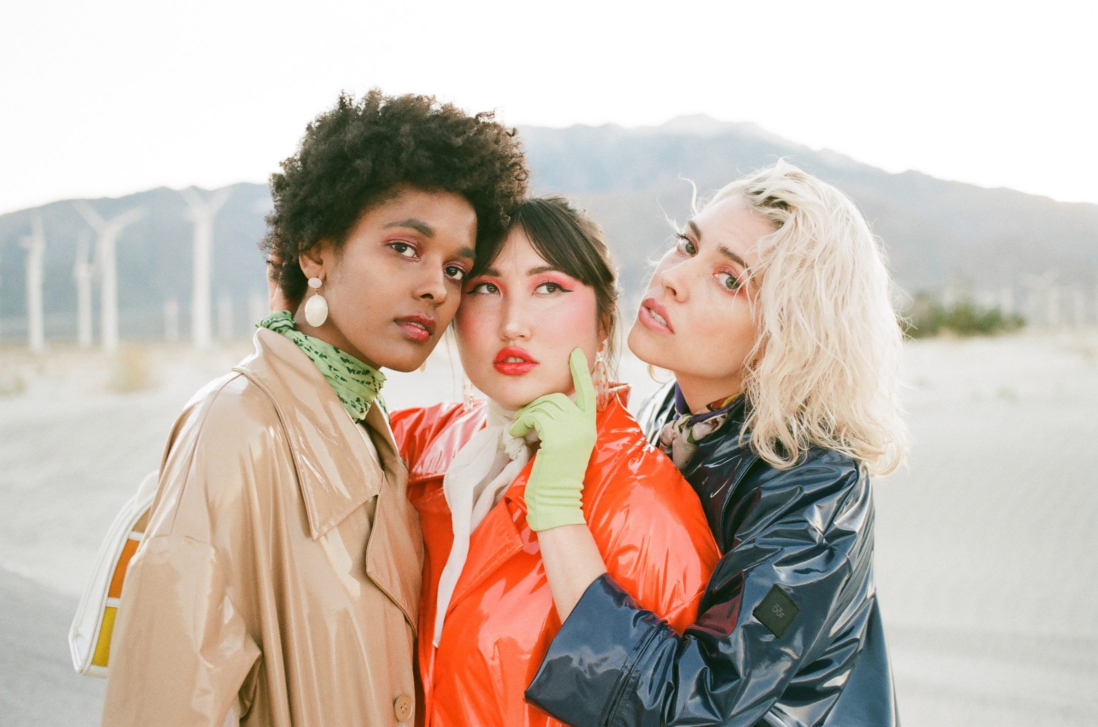 Three women in saturated colour against a desert wind farm