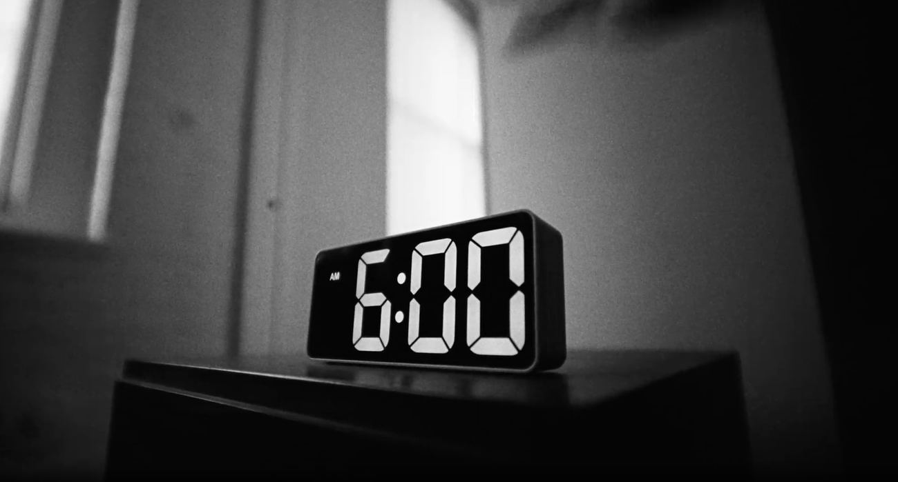 Black and white frame of an alarm clock at 6:00